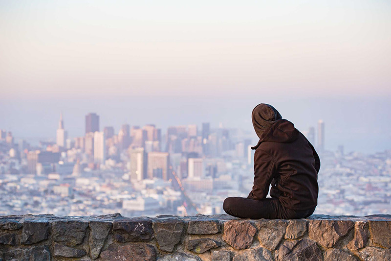Quando finisce un amore. Ragazzo su muretto che guarda panorama di città